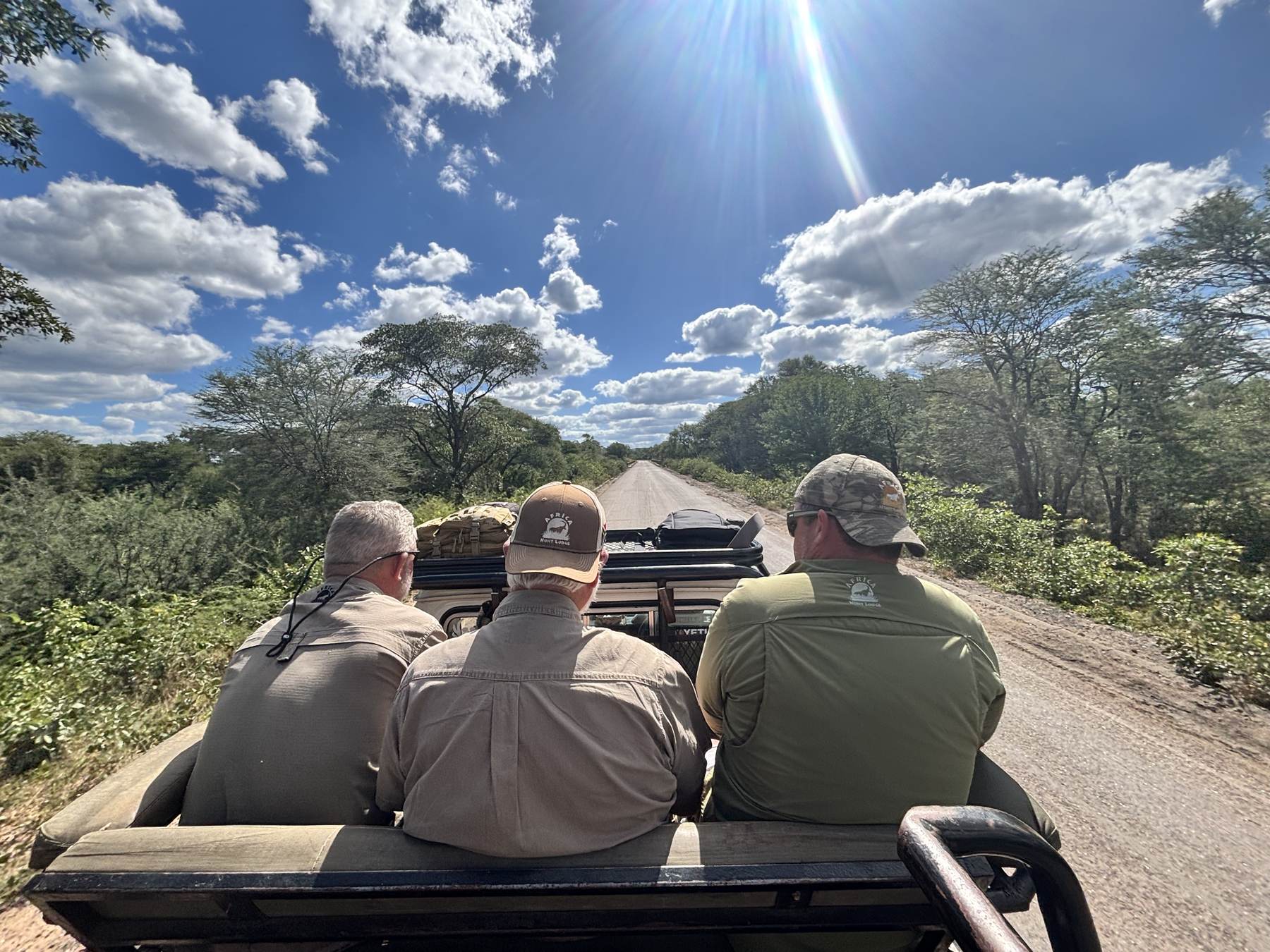 Hunting party riding the back of the vehicle along a bush track in Zimbabwe with Nhoro Safaris